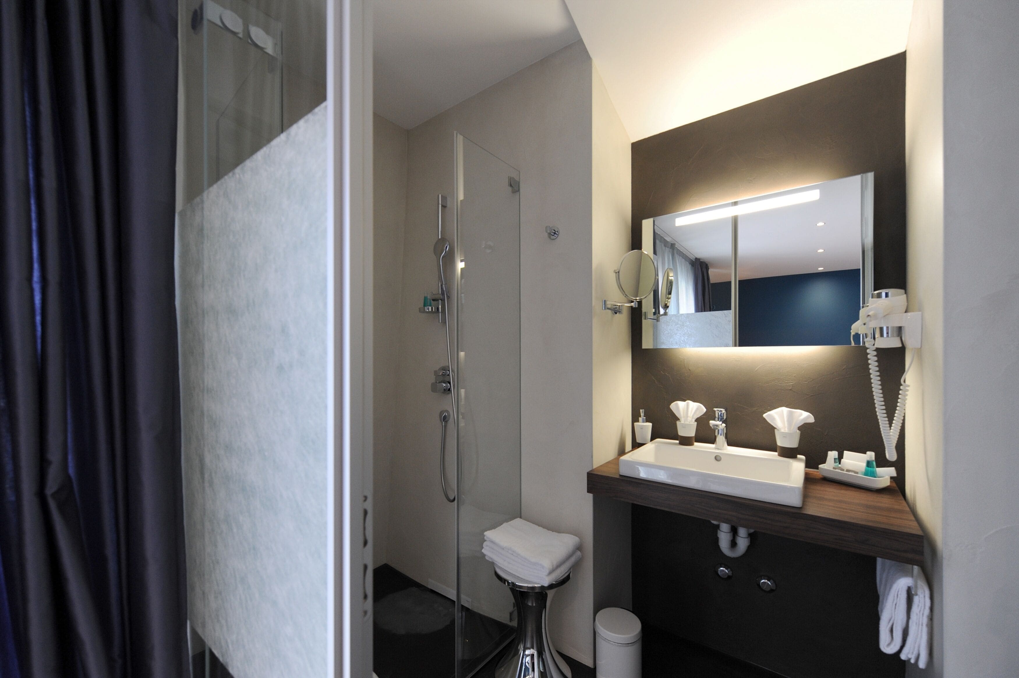 A modern bathroom with a glass-enclosed shower, a sink with a mirror above it, and a towel rack.