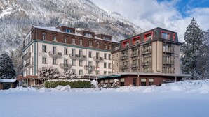 Un hotel con varios pisos, balcones y vistas a montañas nevadas.