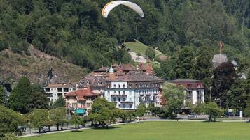 A town with historic buildings, a grassy field, and a person paragliding.
