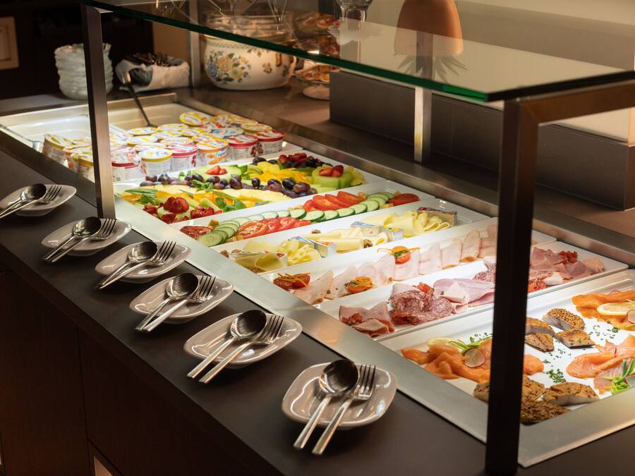 A buffet with various food options and utensils laid out on the counter.