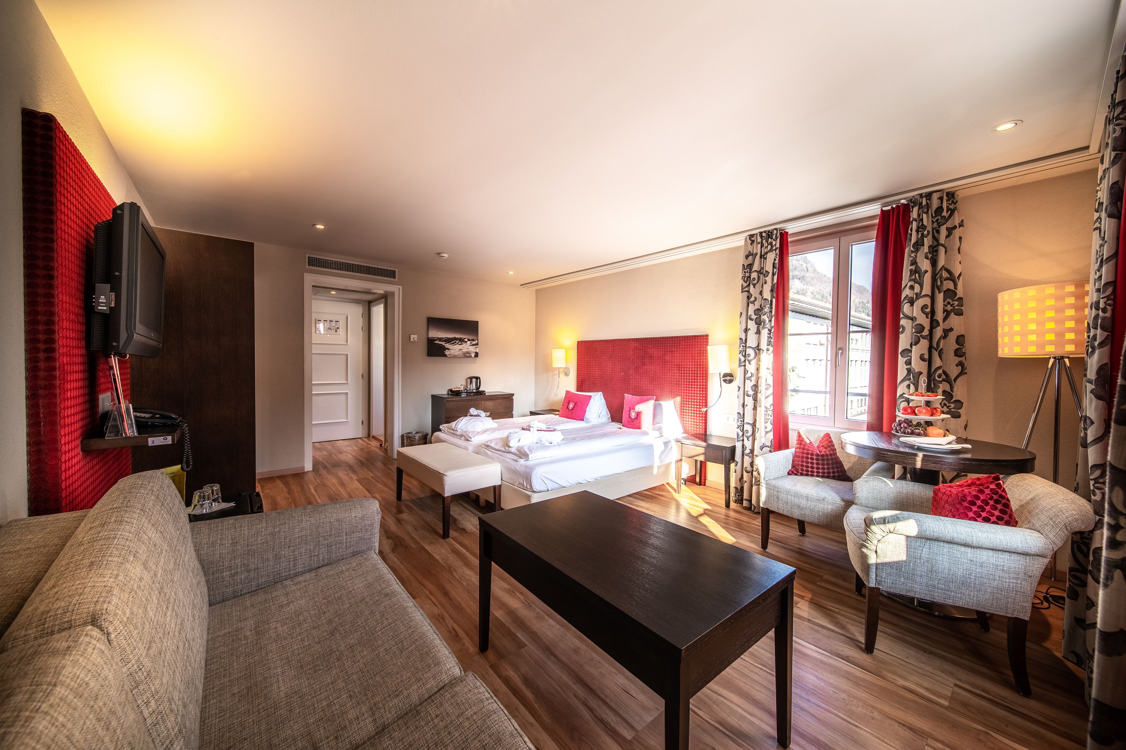 Ein Hotelzimmer mit einem Bett, einem Schlafsofa, einem Couchtisch, einem Fernseher und einem Schreibtisch mit Lampe.