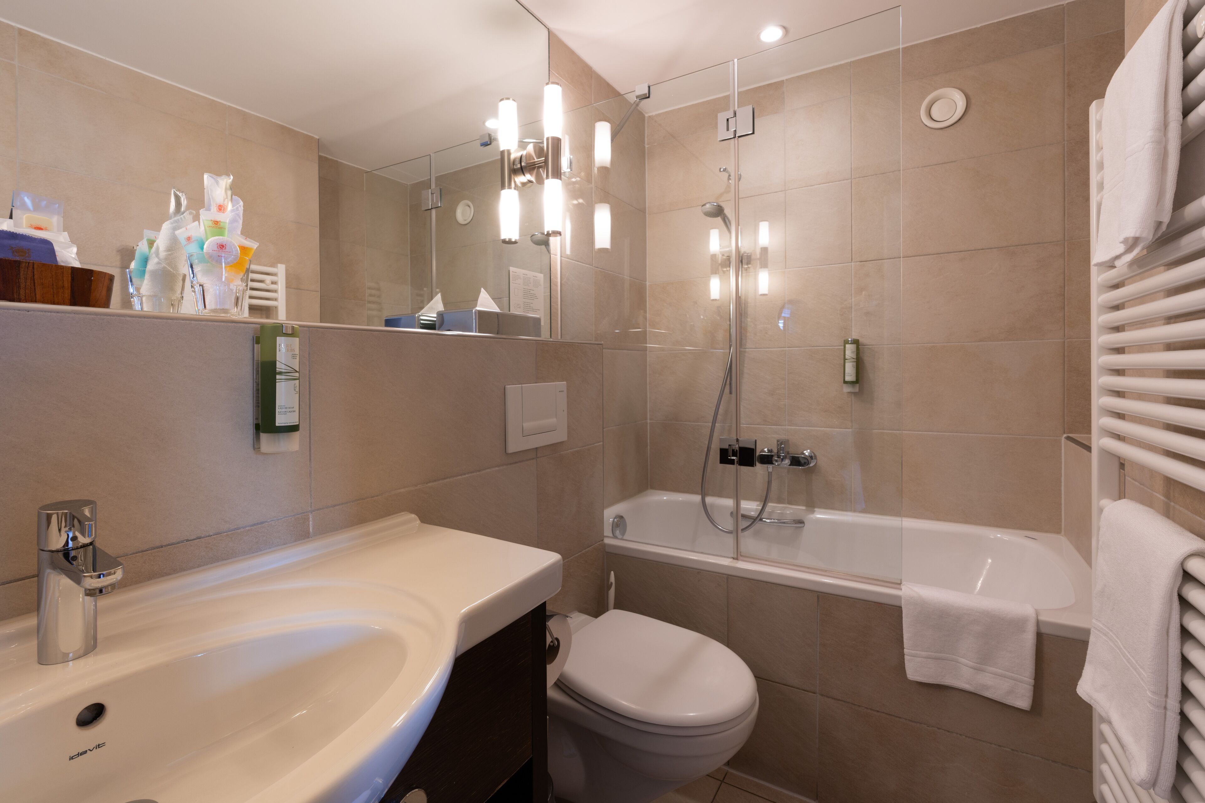 A modern bathroom with a sink, toilet, and bathtub.