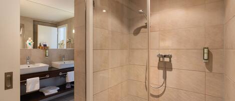 A modern bathroom with two sinks, a glass-enclosed shower, and a large mirror.
