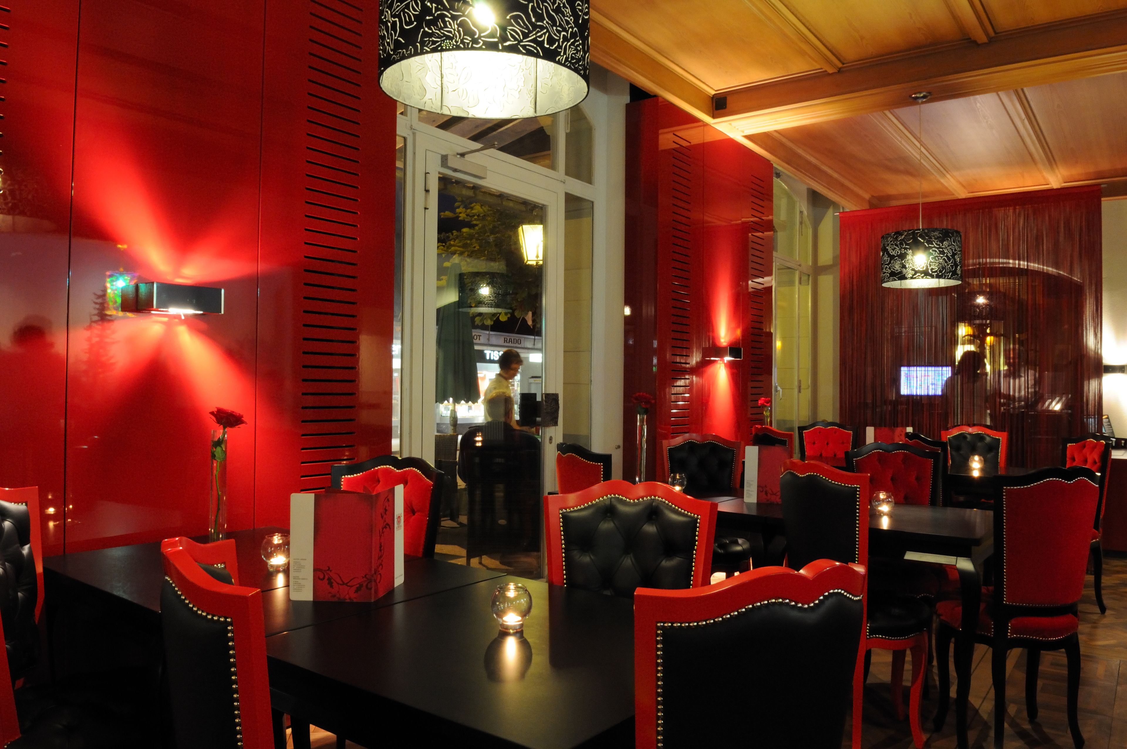 A restaurant with red and black decor, including red chairs and a black table.