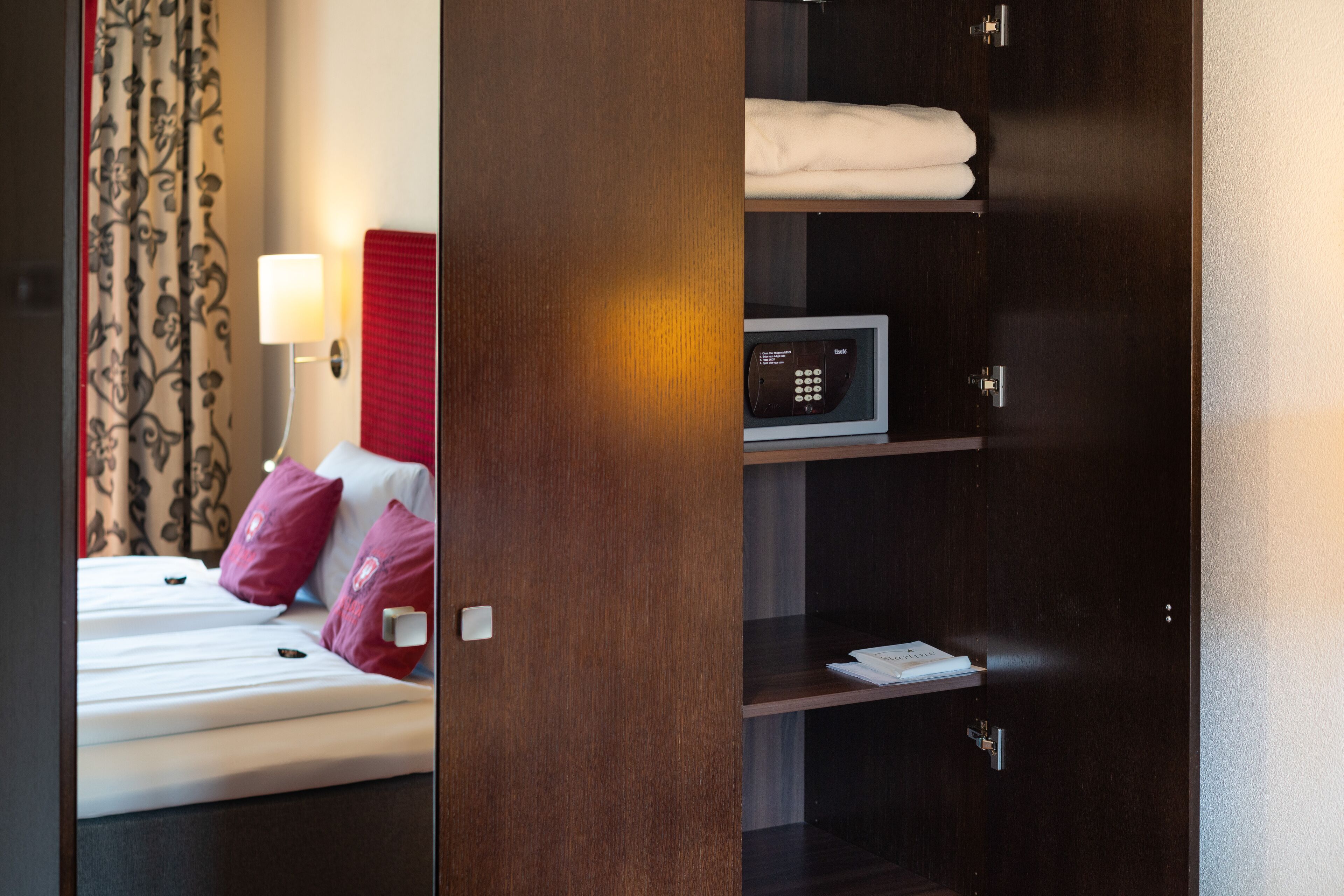 Une chambre d’hôtel avec un lit, un four à micro-ondes et une étagère sur laquelle se trouve un livre.