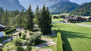 Un paysage montagneux comprenant un terrain de golf, des maisons et une aire de jeux.