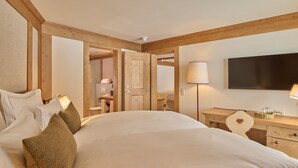 Une chambre à coucher avec un grand lit, une tête de lit en bois, des tables de chevet, un téléviseur à écran plat et une lampe.