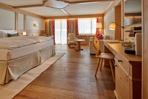 A hotel room with a large bed, a desk, a chair, and a small table.