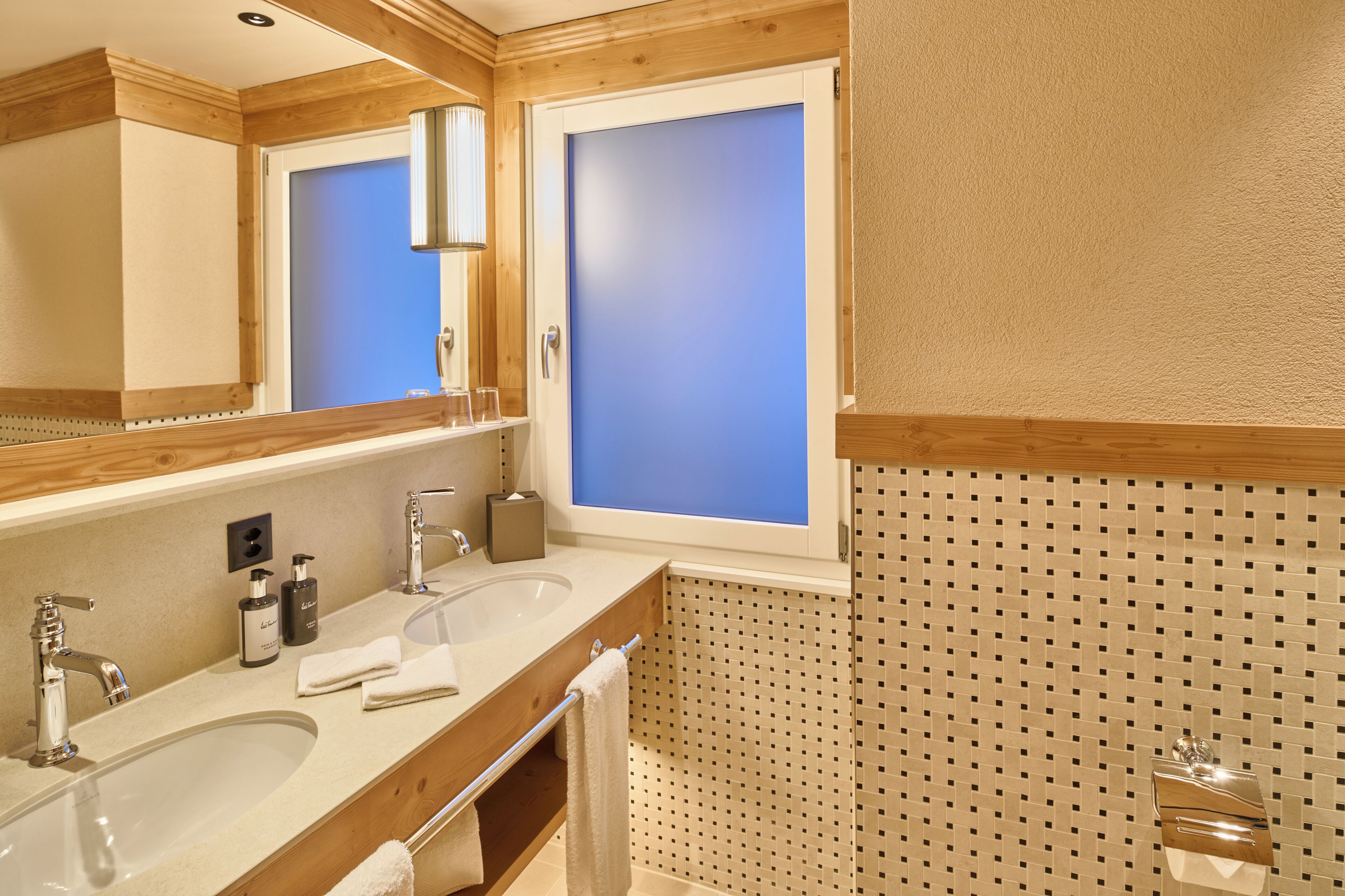 Un baño con dos lavamanos, un espejo y una zona de ducha.