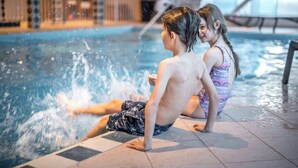 Deux enfants jouent dans une piscine, l’eau éclabousse tout autour d’eux.