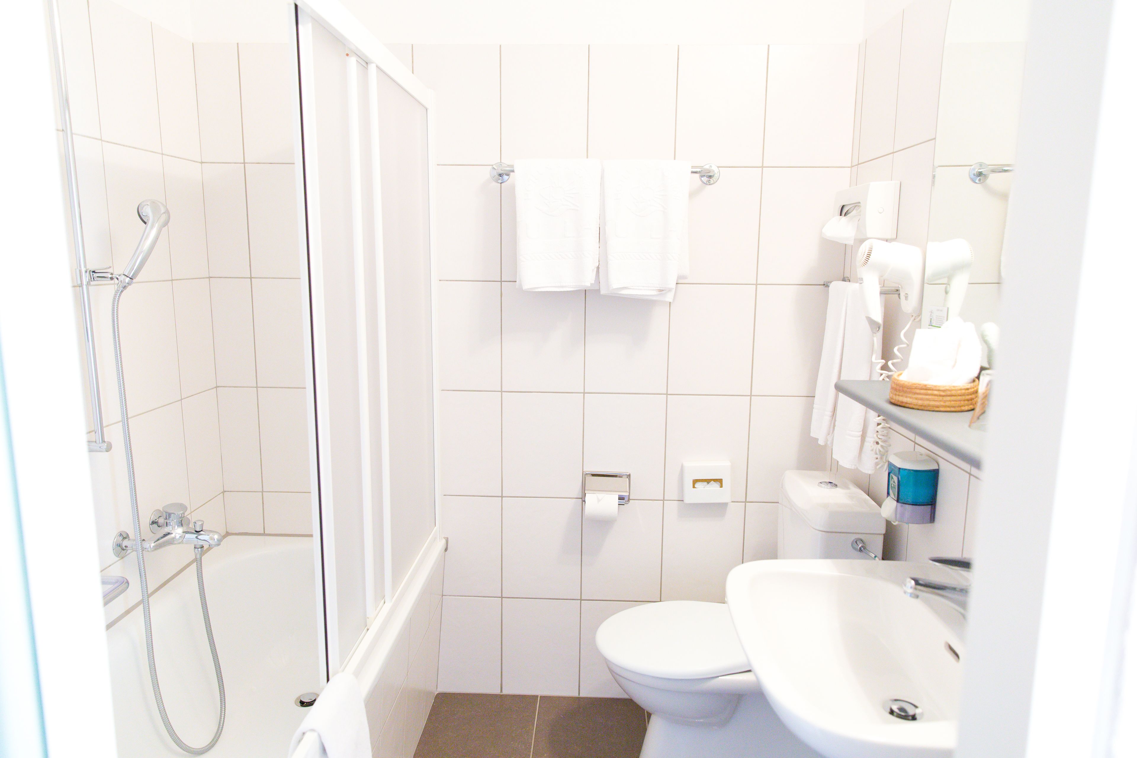 A bathroom with a shower, toilet, sink, and towel rack.
