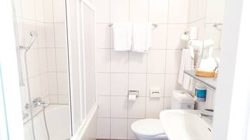 A bathroom with a shower, toilet, sink, and towel rack.