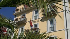 A building with balconies adorned with flowers and a flag. - Hotel DU LAC Locarno (Locarno)