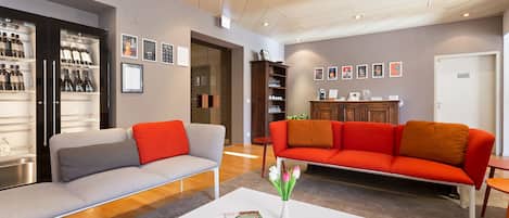 Una sala de estar moderna con un sofá gris, un sofá naranja, una mesa de centro blanca y una estantería.