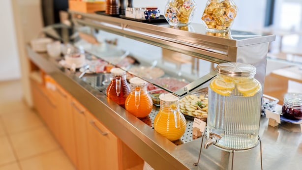 A buffet with various food items and beverages, including jars of honey and orange juice. - Hotel Muralto (Muralto)
