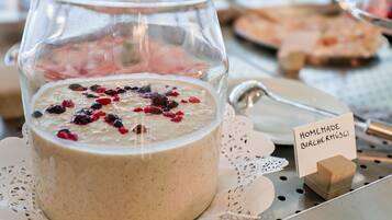 Un frasco de vidrio con bircher muesli casero y bayas sobre una bandeja de metal.