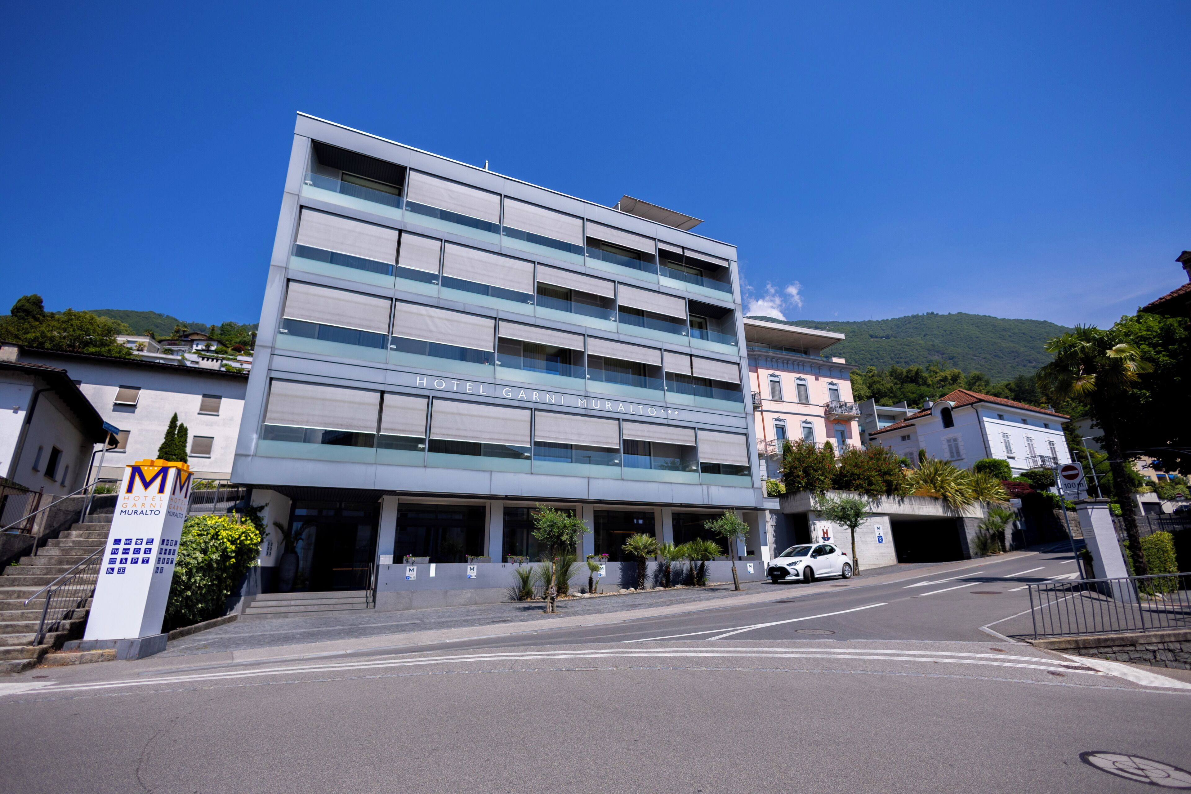 A modern hotel with a multi-story structure, a covered entrance, and a parking area.