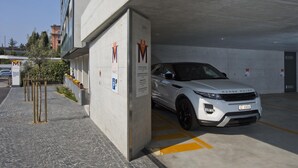 A white Range Rover parked in a covered parking area with a concrete wall and a sign with the letter "M". - Hotel Muralto (Muralto)