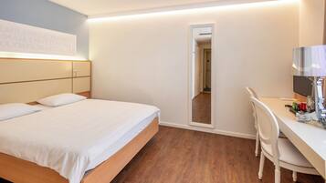 A hotel room with a bed, a desk, a chair, a mirror, and a wall with text.