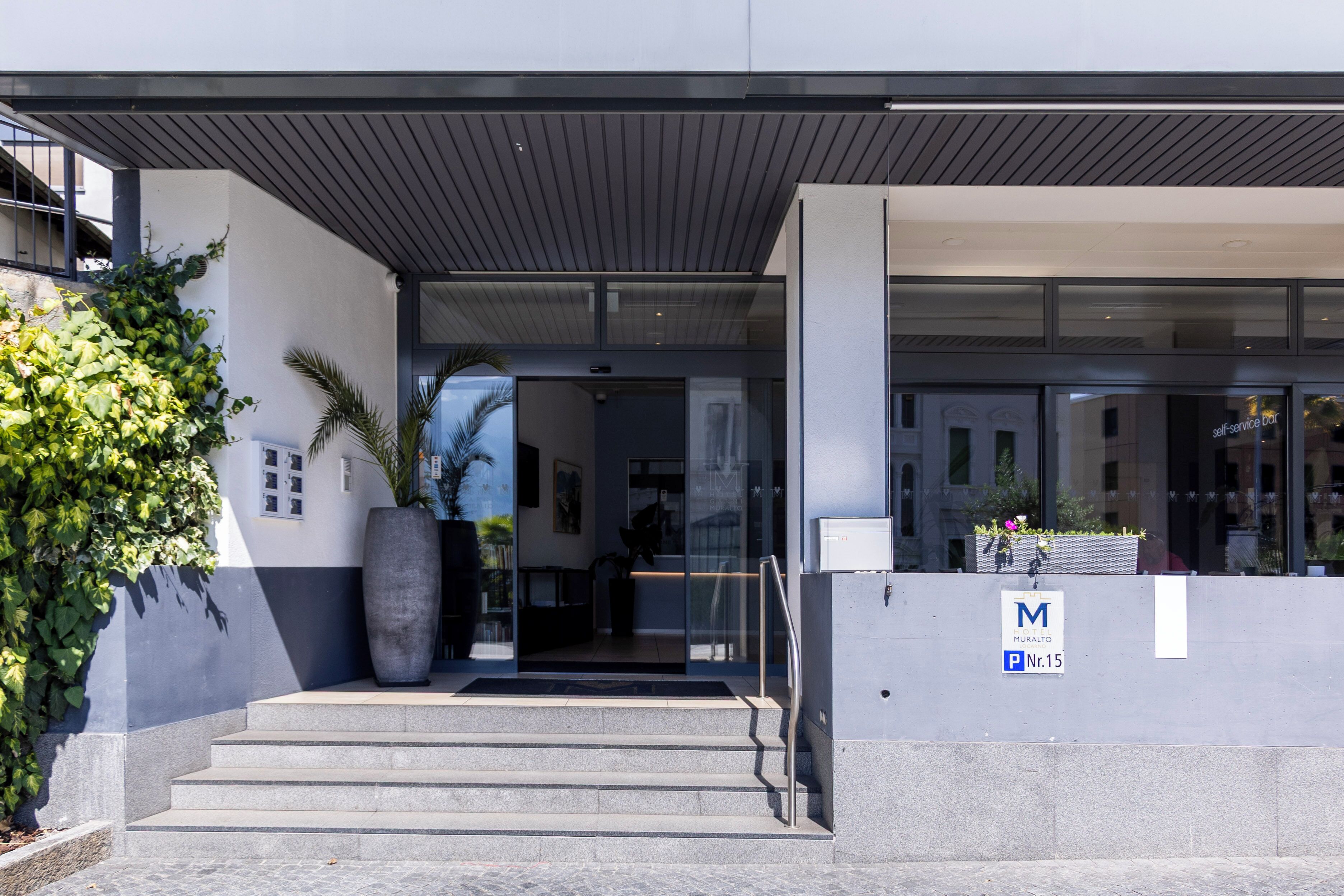 Een modern gebouw met een glazen deur, een trap en een parkeersbord.