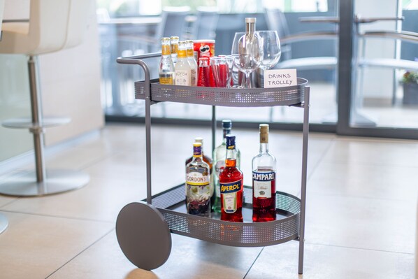 A metal cart with bottles and glasses labeled "Drinks Trolley" in a modern indoor setting. - Hotel Muralto (Muralto)