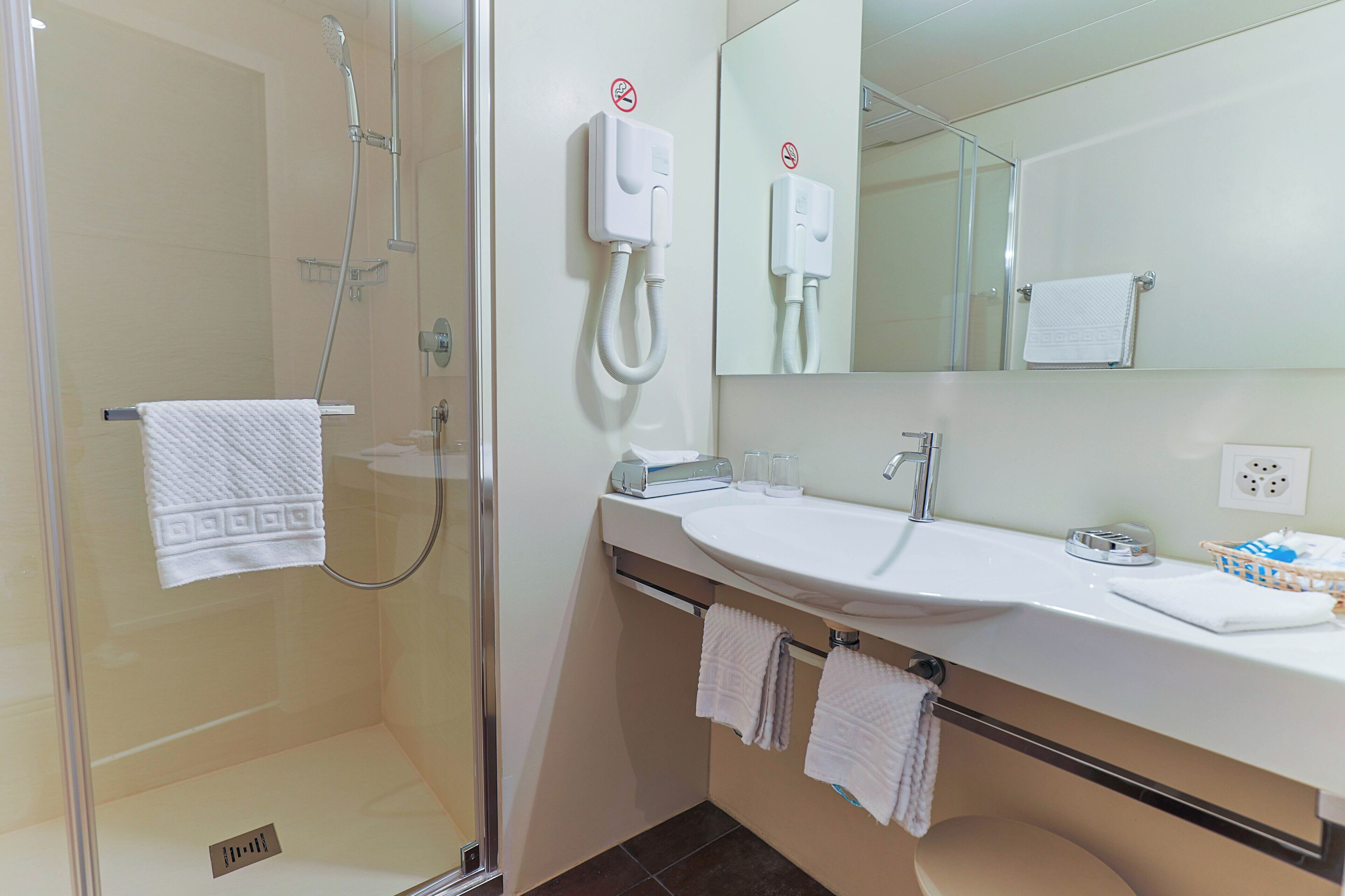 A modern bathroom with a glass-enclosed shower, a sink with a mirror, and a towel rack.