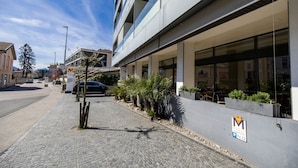 A modern building with a paved sidewalk, outdoor seating area, and a parking sign. - Hotel Muralto (Muralto)