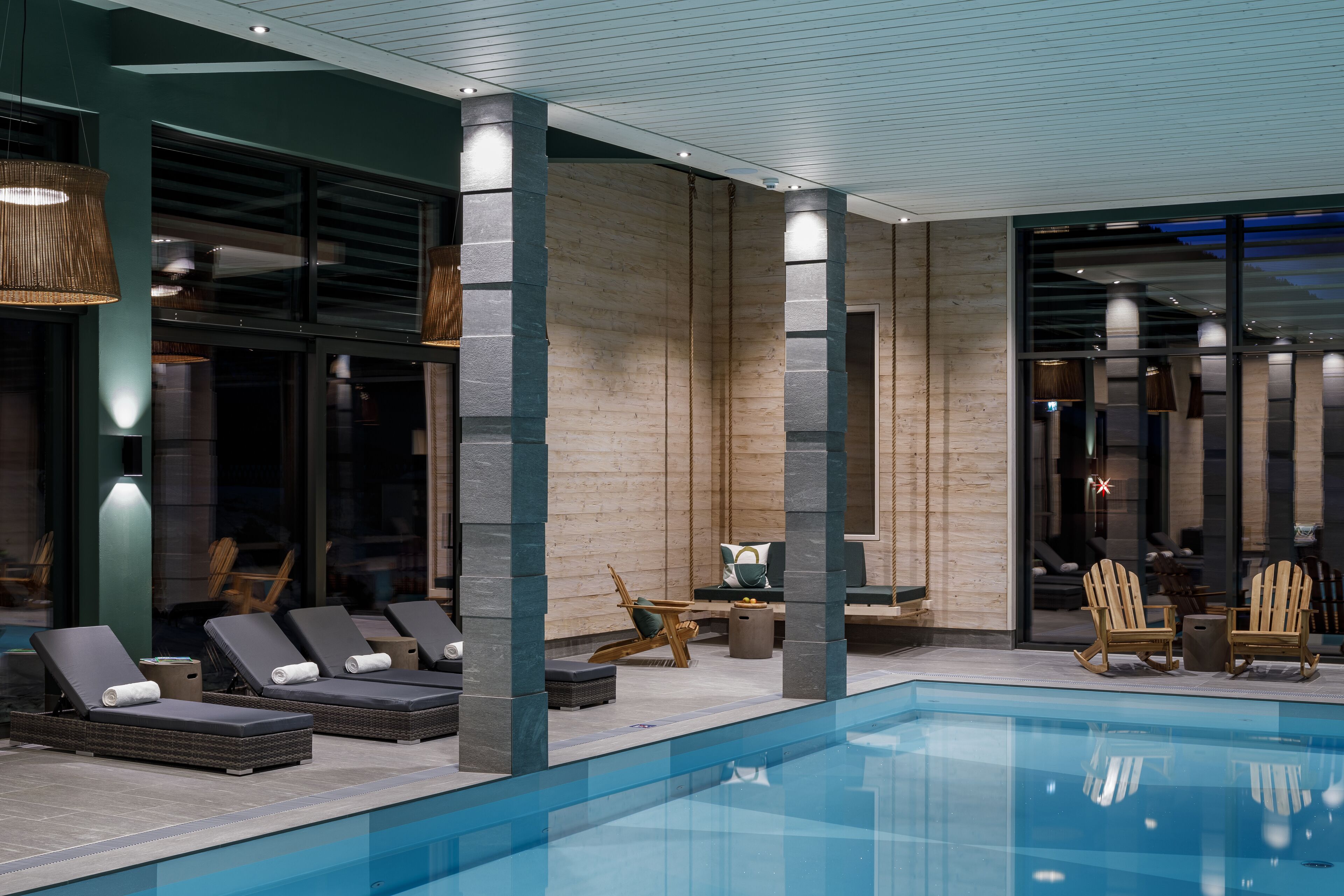 Un área de piscina interior moderna con sillones de descanso y zona de estar.