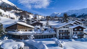 A hotel with multiple buildings, snow-covered surroundings, and a mountainous backdrop.