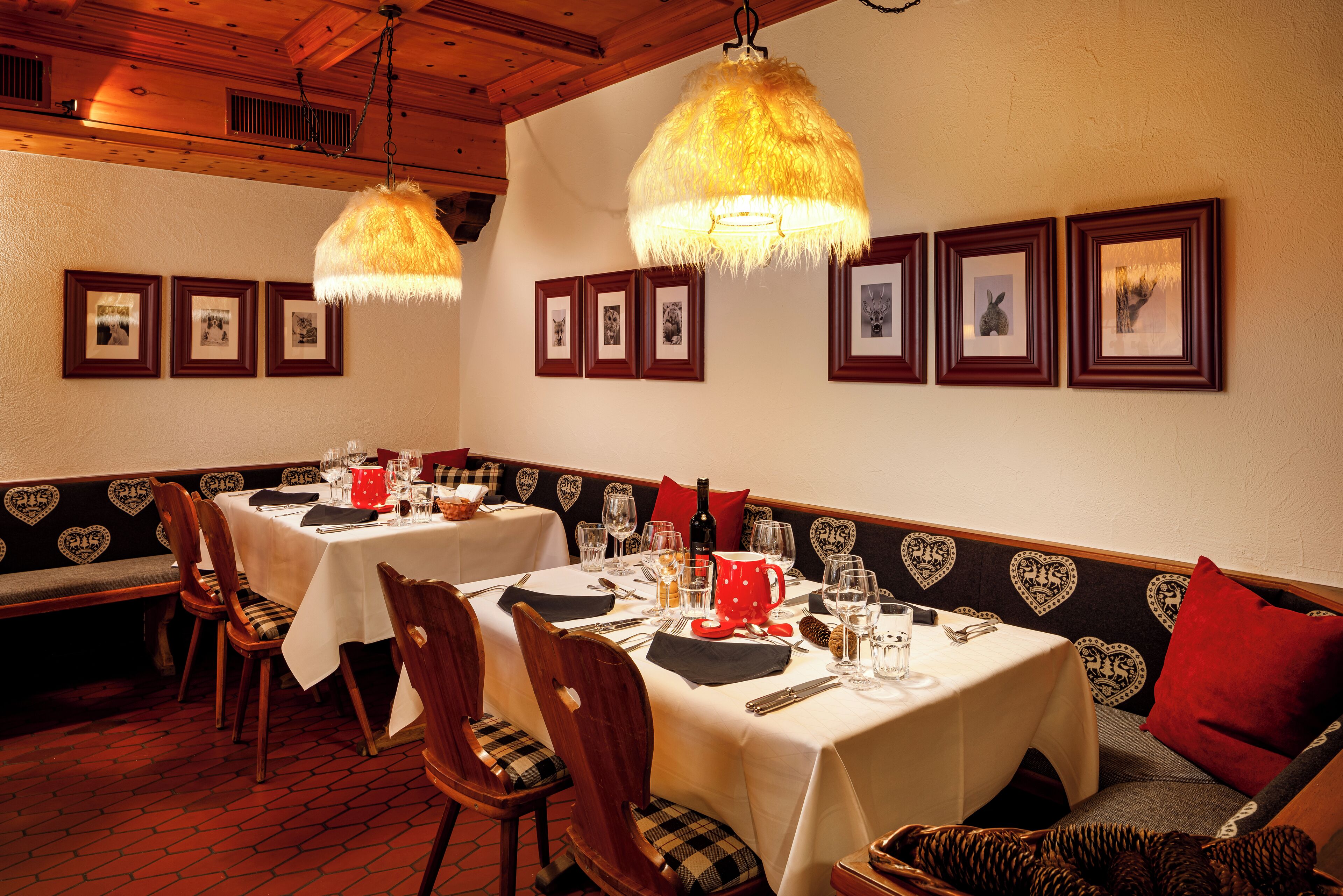 A restaurant with heart-patterned booths, white tablecloths, and hanging lamps.