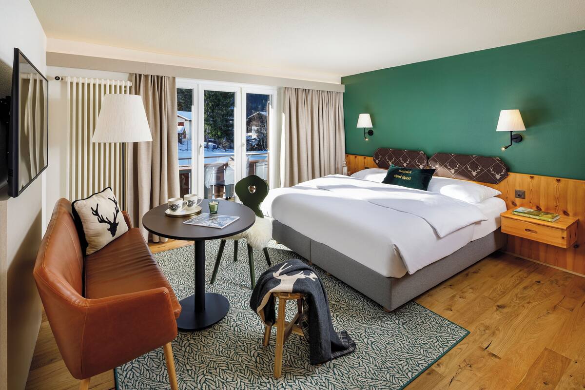 A hotel room with a bed, a sofa, a small table, and a chair.