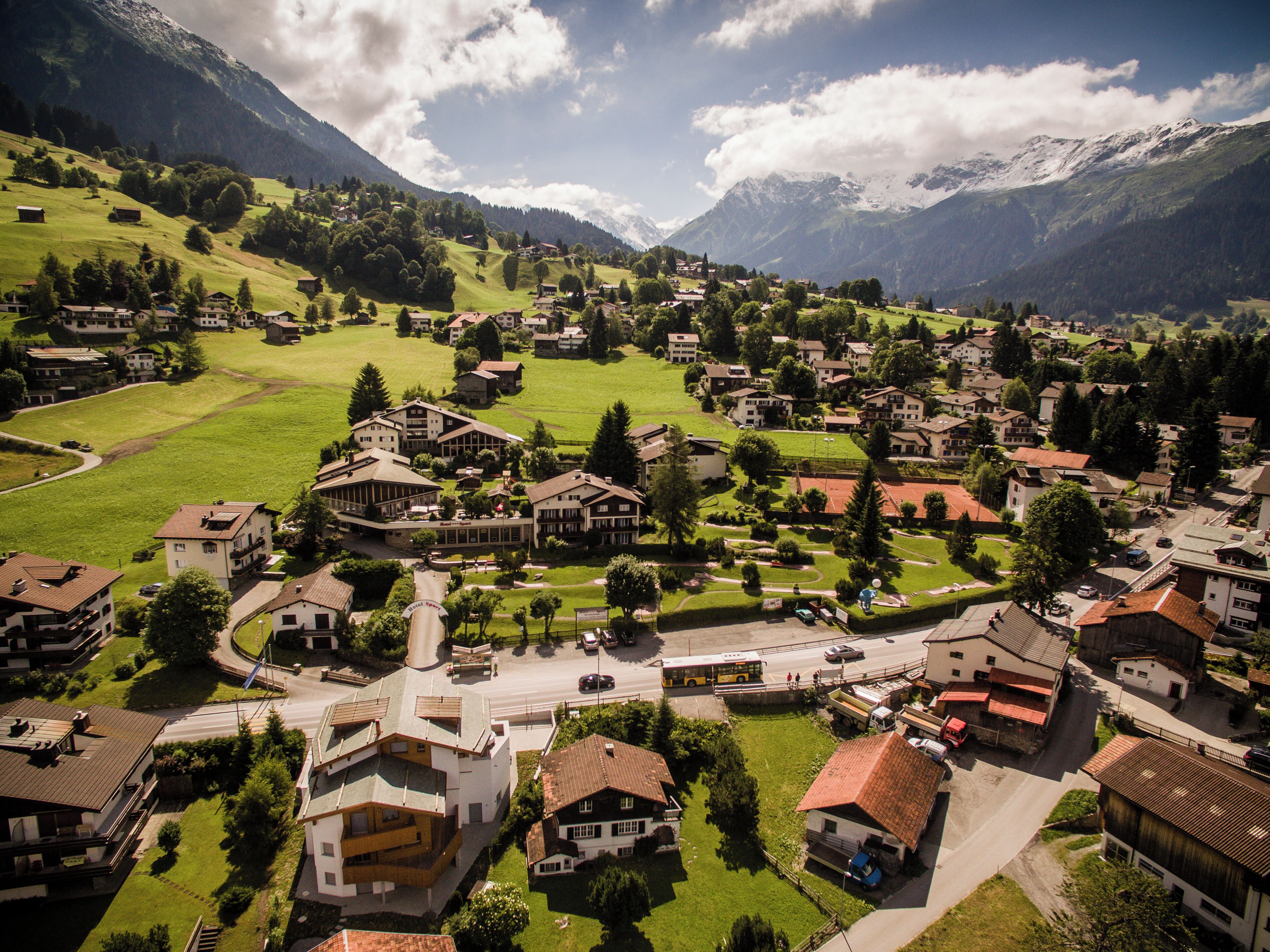 A mountainous village with traditional buildings, a central square, and a bus stop.