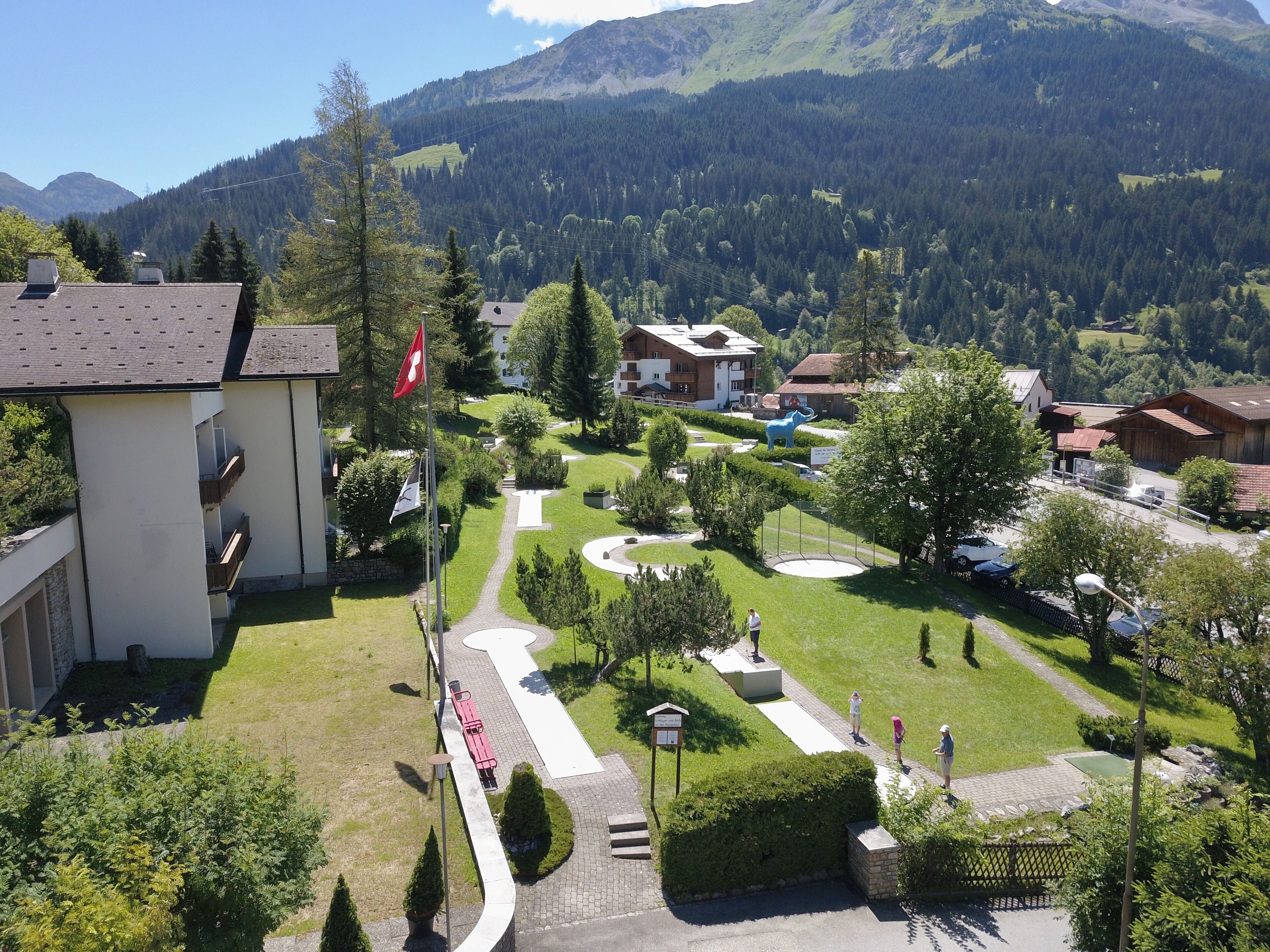 A residential area with a central pathway, houses, and a mountain backdrop.