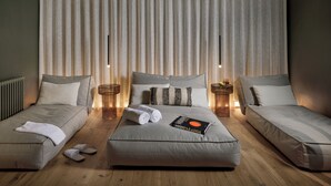 A modern hotel room with a large bed, two smaller beds, and a nightstand with a lamp.