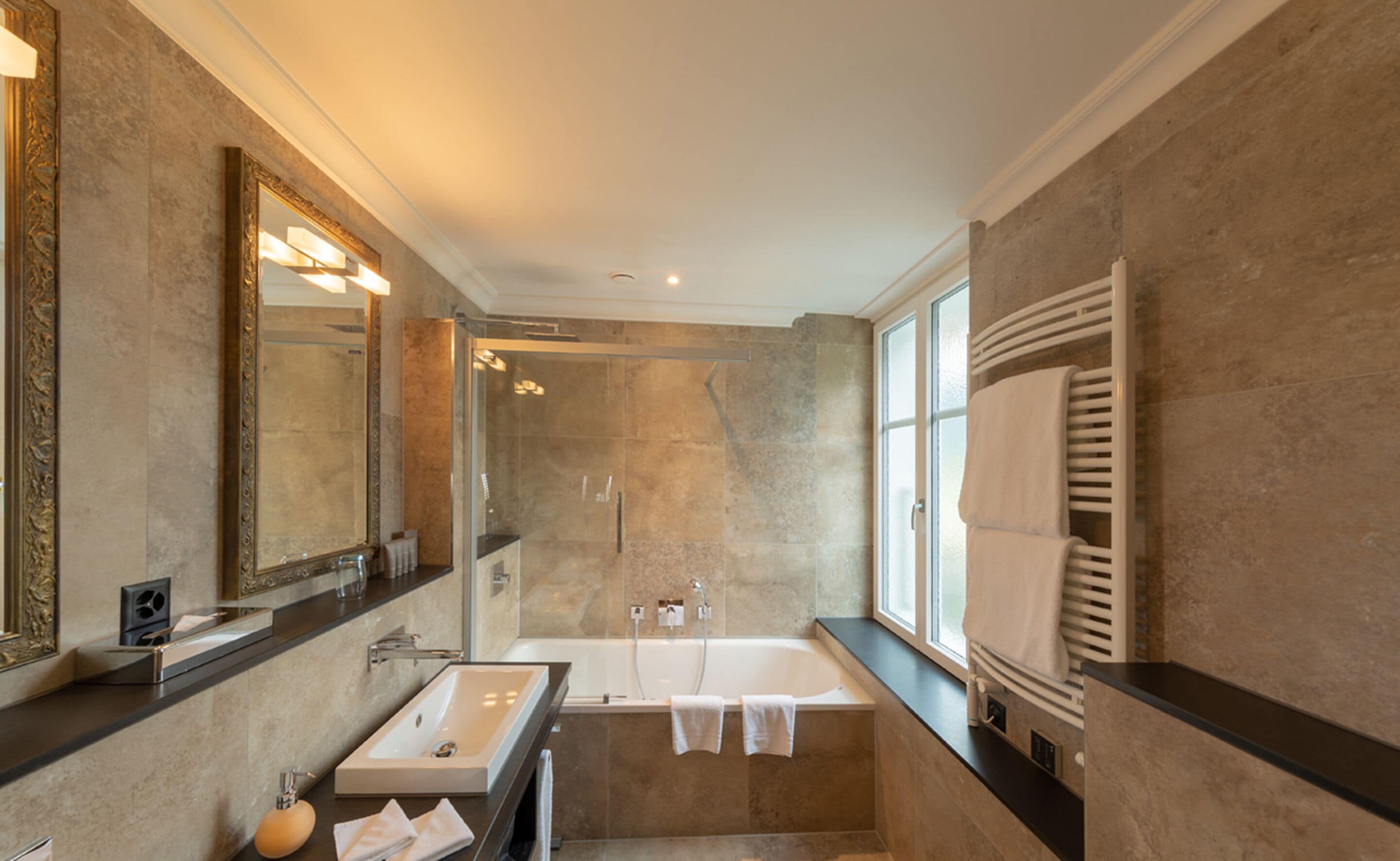 Ein modernes Badezimmer mit einem großen Spiegel, einer Badewanne und einer Dusche.