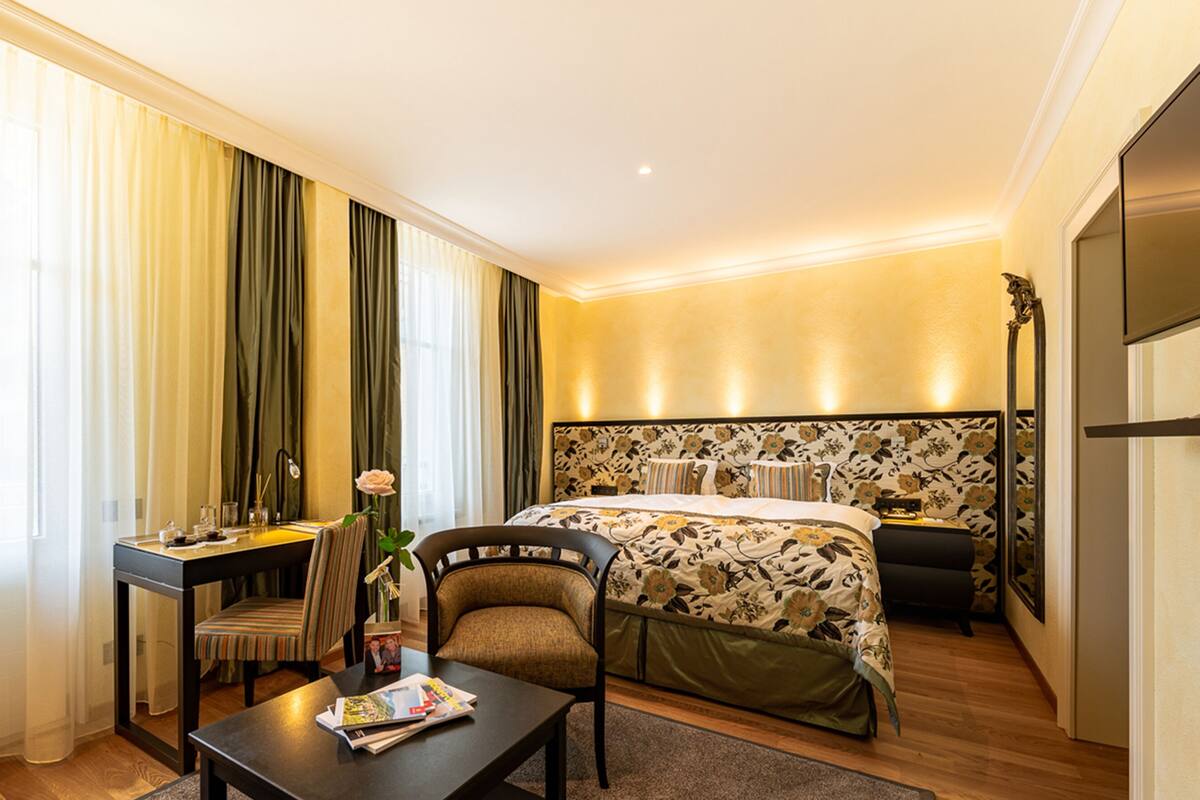 Una habitación de hotel con cama, escritorio, silla y mesa.