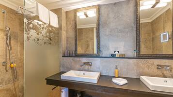 Une salle de bain avec un grand miroir, deux lavabos et une douche.