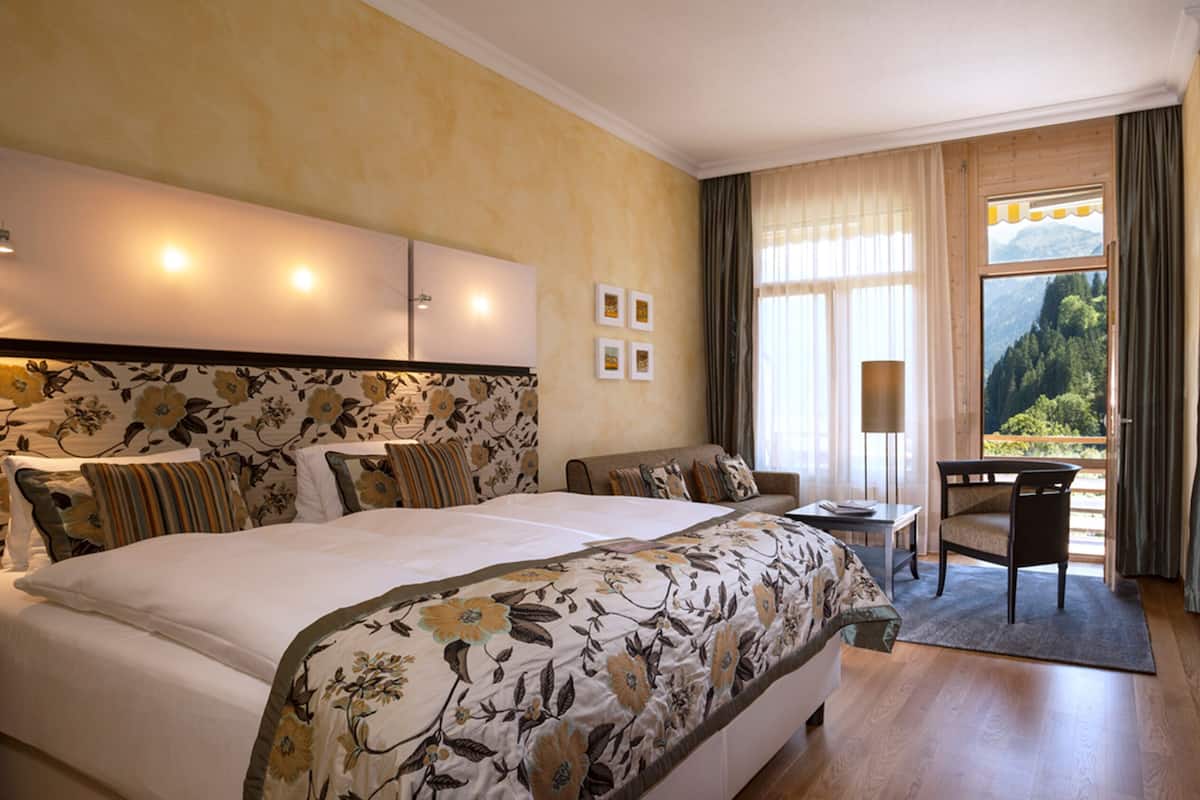 Una habitación de hotel con una cama grande, un sofá, un escritorio y vistas al exterior.