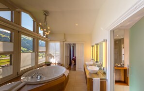 A spacious bathroom with a large bathtub, two sinks, and a vanity with a mirror.