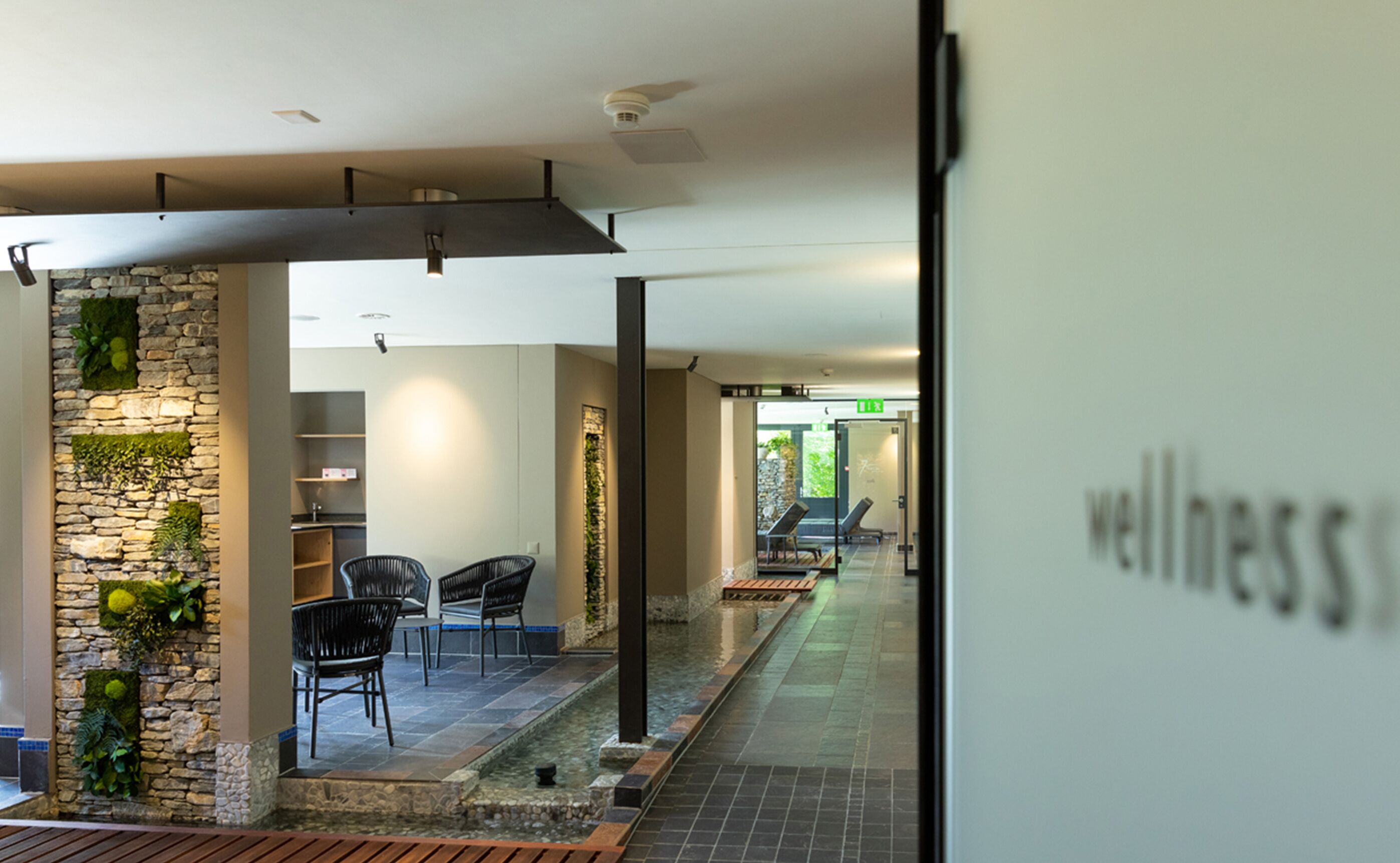 A corridor with a stone wall, chairs, and a wellness sign.