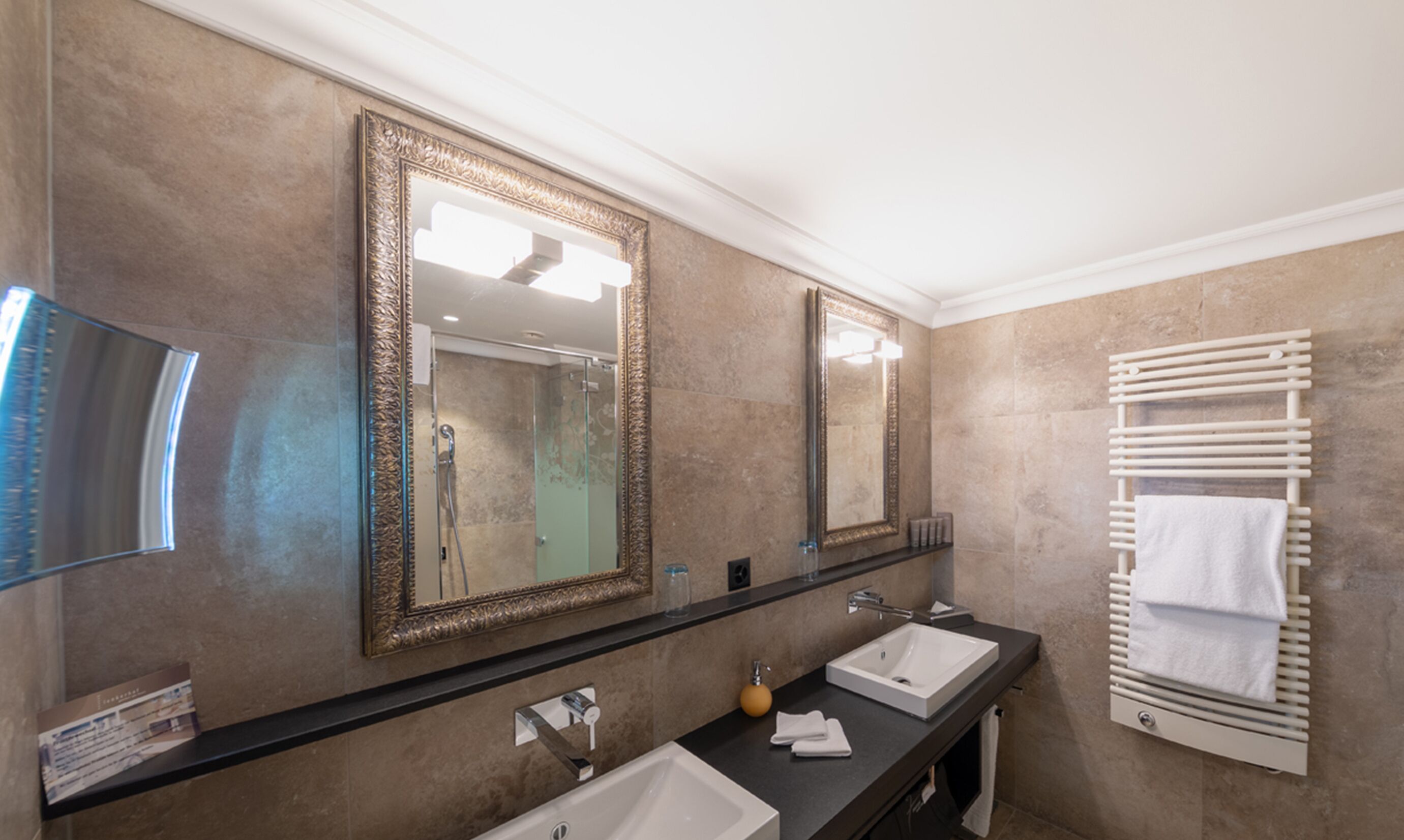 Une salle de bain avec deux lavabos, un grand miroir et un porte-serviettes.