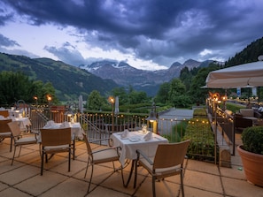 An outdoor dining area with tables and chairs, overlooking a mountainous landscape. - Lenkerhof Gourmet Spa Resort (Lenk)