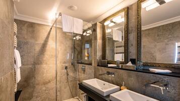 Un baño moderno con cabina de ducha de vidrio, dos lavabos y un espejo grande con marcos ornamentados.