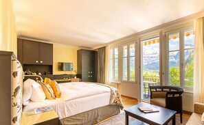 A hotel room with a large bed, a desk, a chair, and a balcony with a mountain view. - Lenkerhof Gourmet Spa Resort (Lenk)