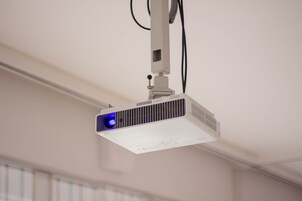 Proyector instalado en el techo, con cable de alimentación visible.