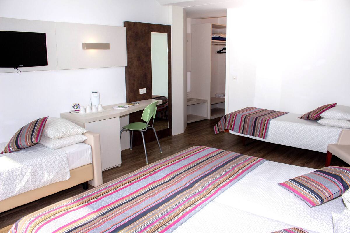 Ett hotellrum med två separata sängar, ett skrivbord, en stol, en TV och en garderob.