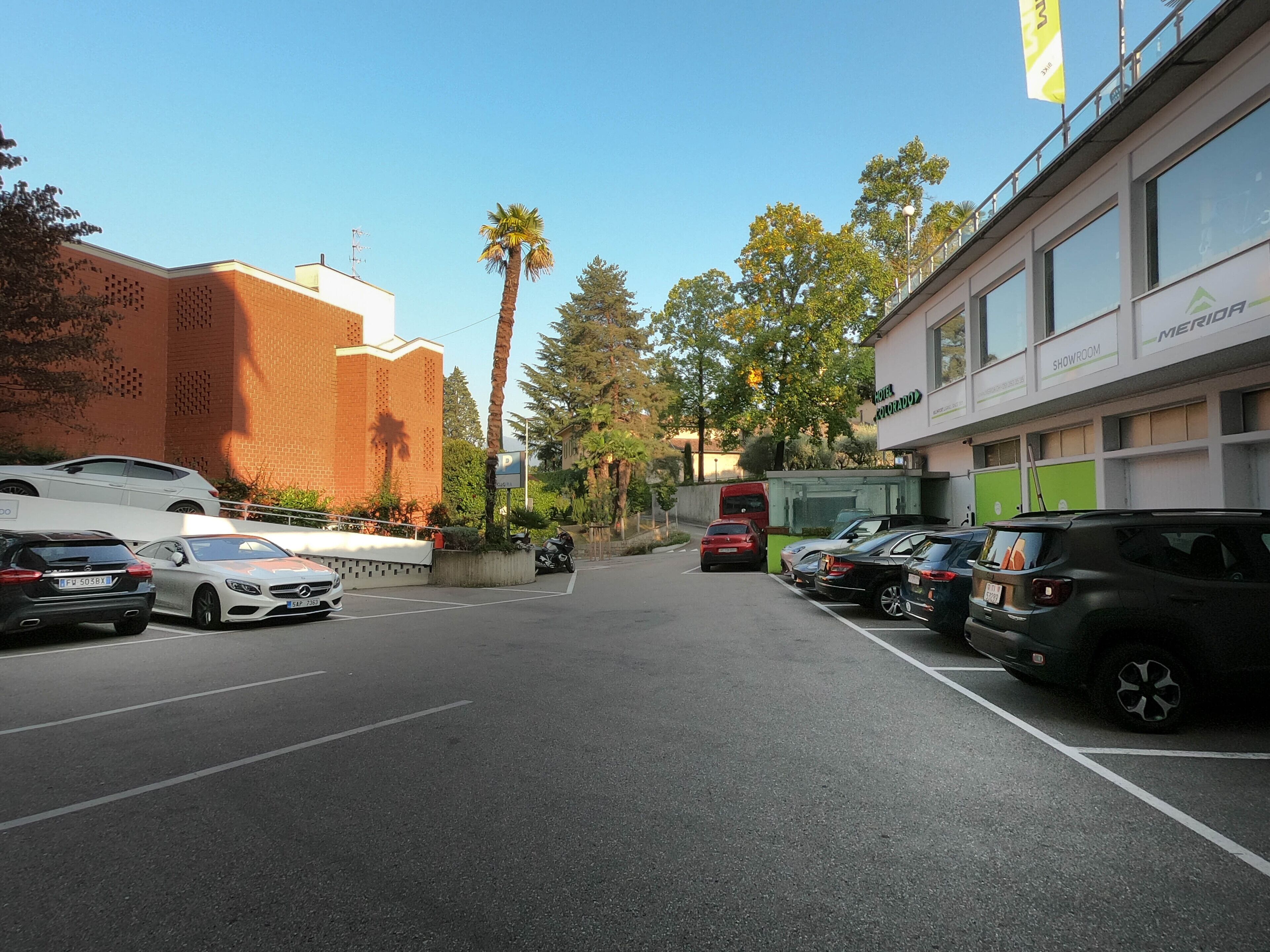 A parking lot with multiple cars, a red bus, and a building with a 'Showroom' sign.