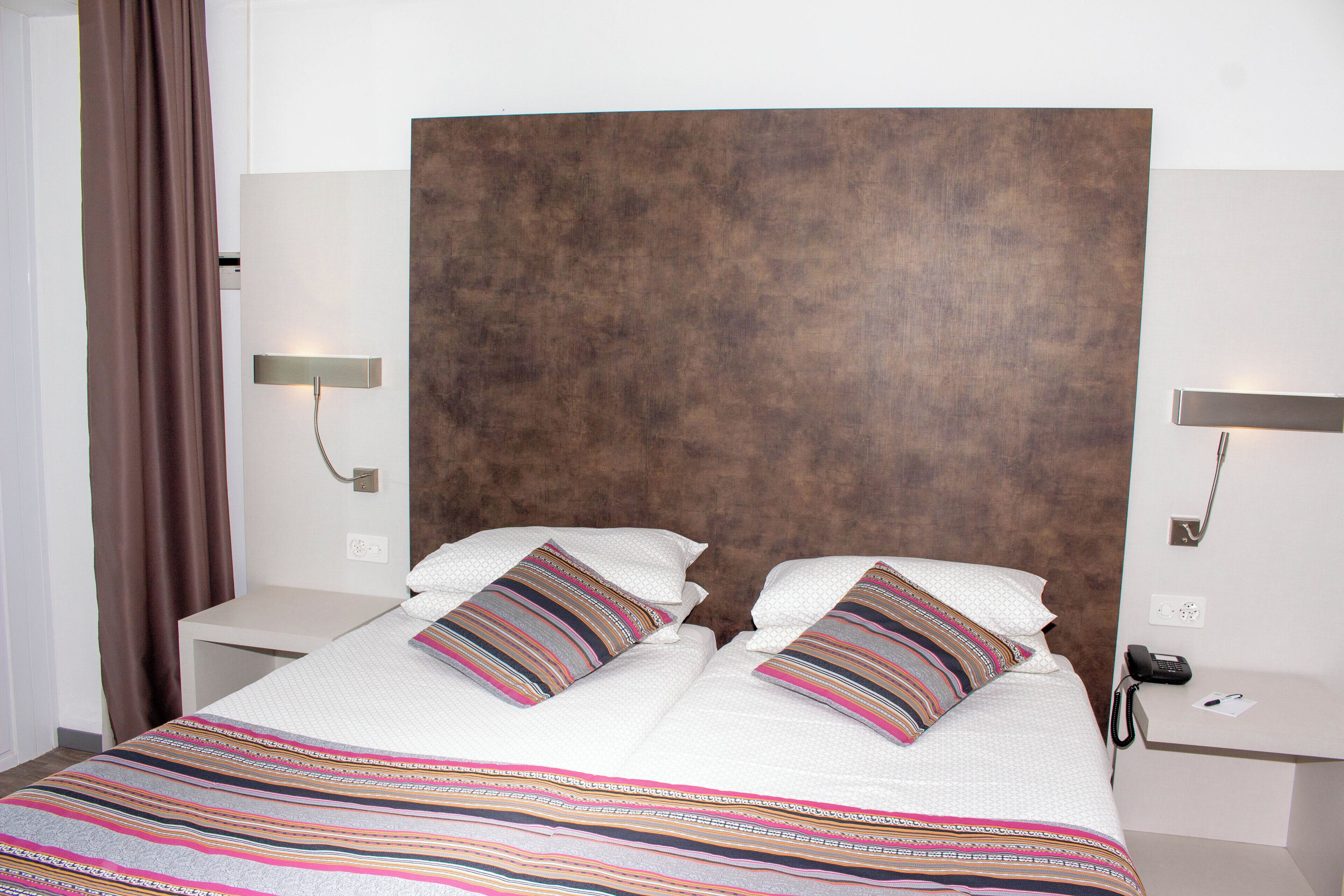 A neatly made bed with striped bedding, a wooden headboard, and bedside tables with lamps.