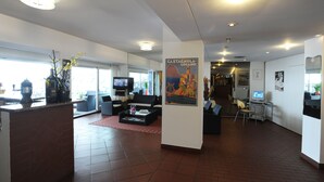Un vestíbulo amplio con mostrador de recepción, zona de estar y un cartel grande.