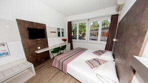 Una habitación de hotel moderna con cama, escritorio, silla, televisor y ventana con cortinas.
